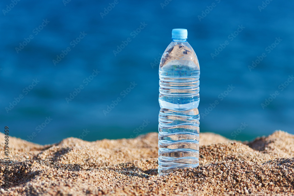 Bottle of pure water on the beach sand against the sea. Bottle of pure water on the beach sand against the sea.