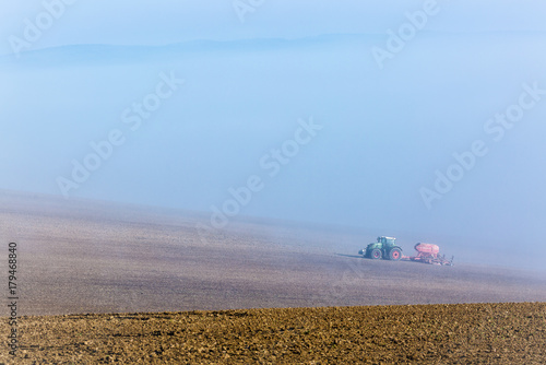 Beautiful misty foggy autumn landscape with working tractor in south moravia, Czech Republic. Agriculture concept.