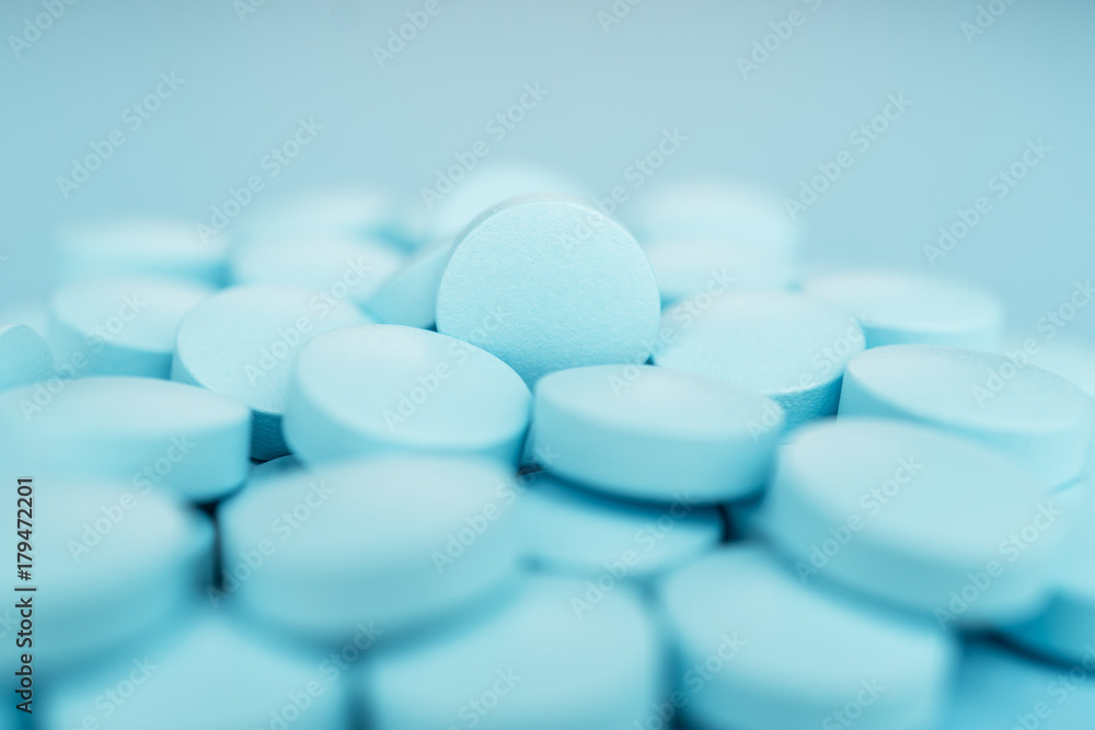 pile of blue pills close-up on the background. shallow depth of field
