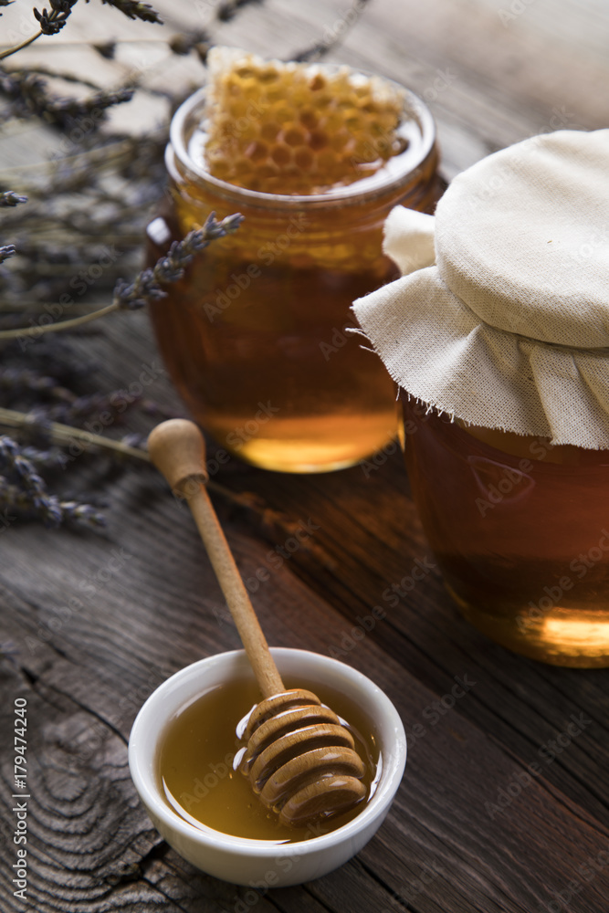 Honey and wooden stick are on a table Honey and wooden stick are on a table