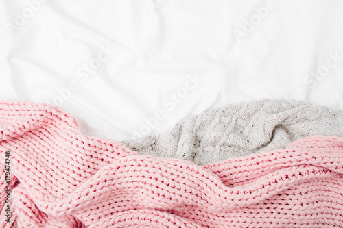 Bedding with a pink knitted plaid. Copy space. Flat lay, top view