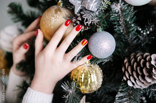 Obraz na plátně Manicure for the New Year in red against the background of Christmas trees and C