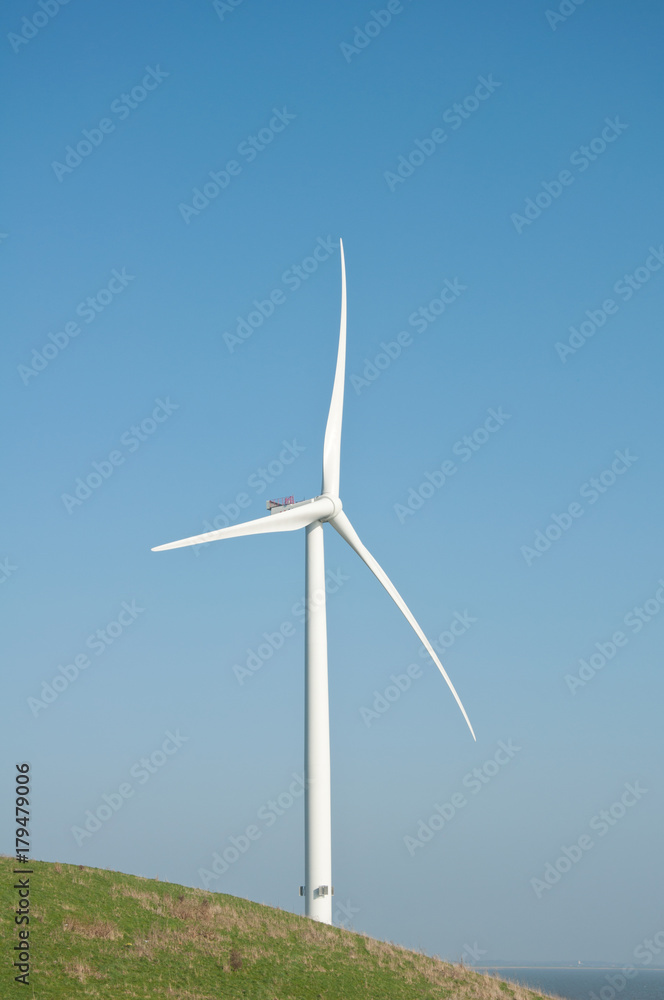 Wind turbine and small green hill and blue sky Wind turbine and small green hill and blue sky