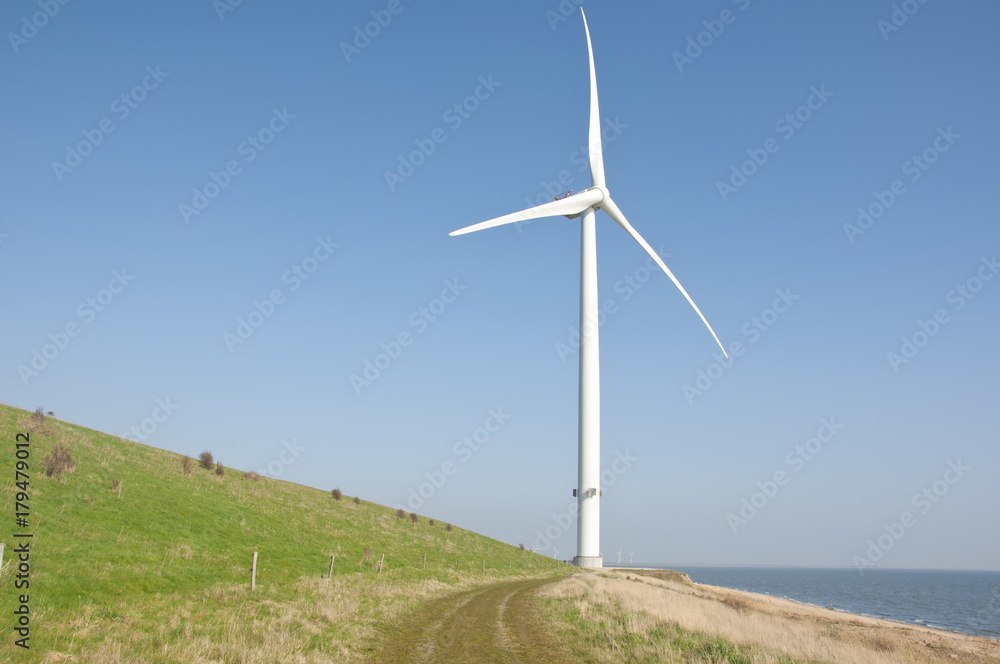Wind turbine with clean blue sky background and green hill Wind turbine with clean blue sky background and green hill
