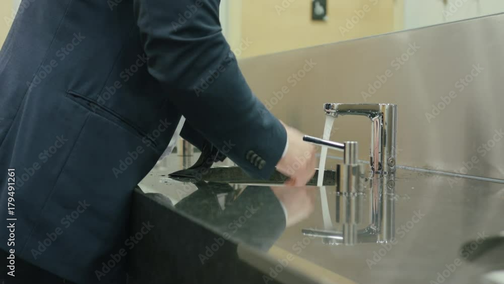 A man washing hands in a public bathroom. Close-up shot A man washing hands in a public bathroom. Close-up shot