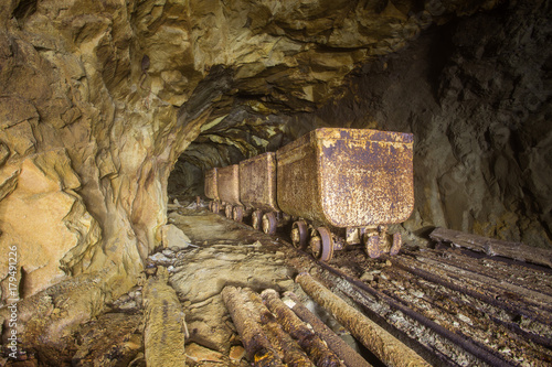 Underground abandoned gold ore mine shaft tunnel gallery passage with ore carts
