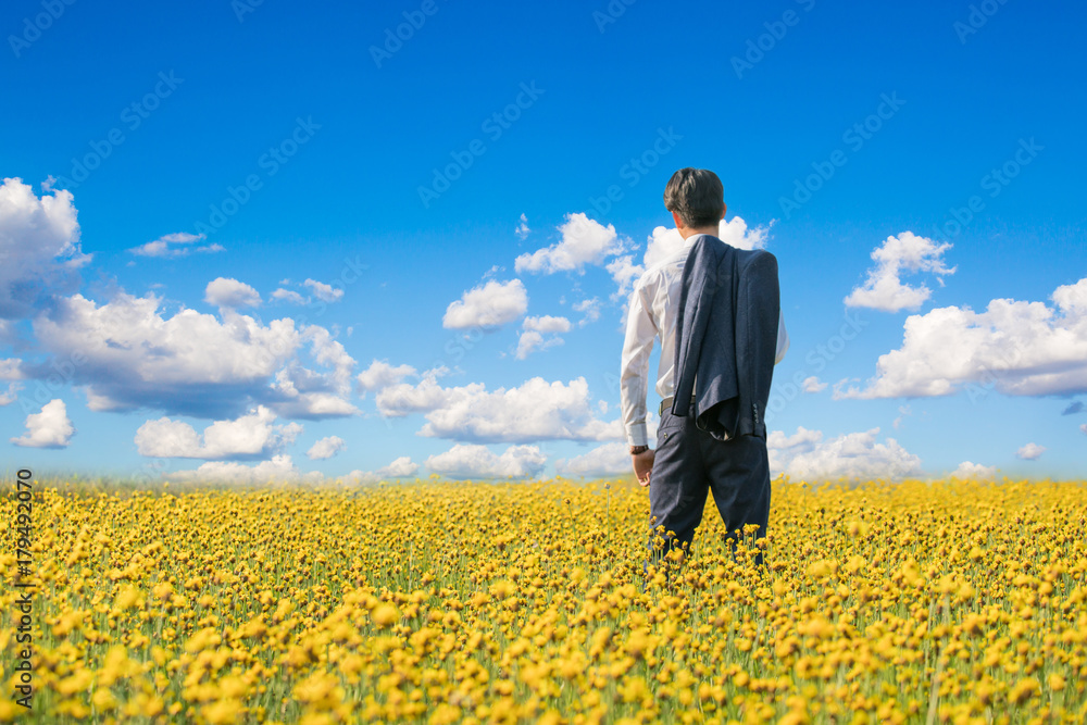 businessman standing in yellow flower field businessman standing in yellow flower field