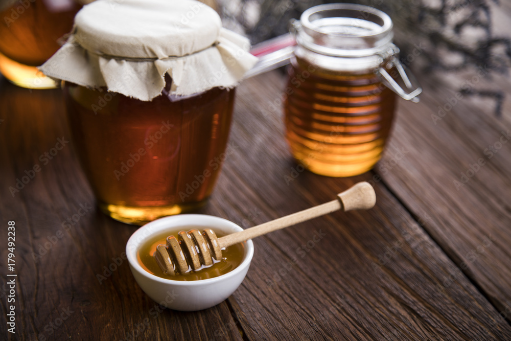Honey dripping from a wooden honey dipper in a jar Honey dripping from a wooden honey dipper in a jar