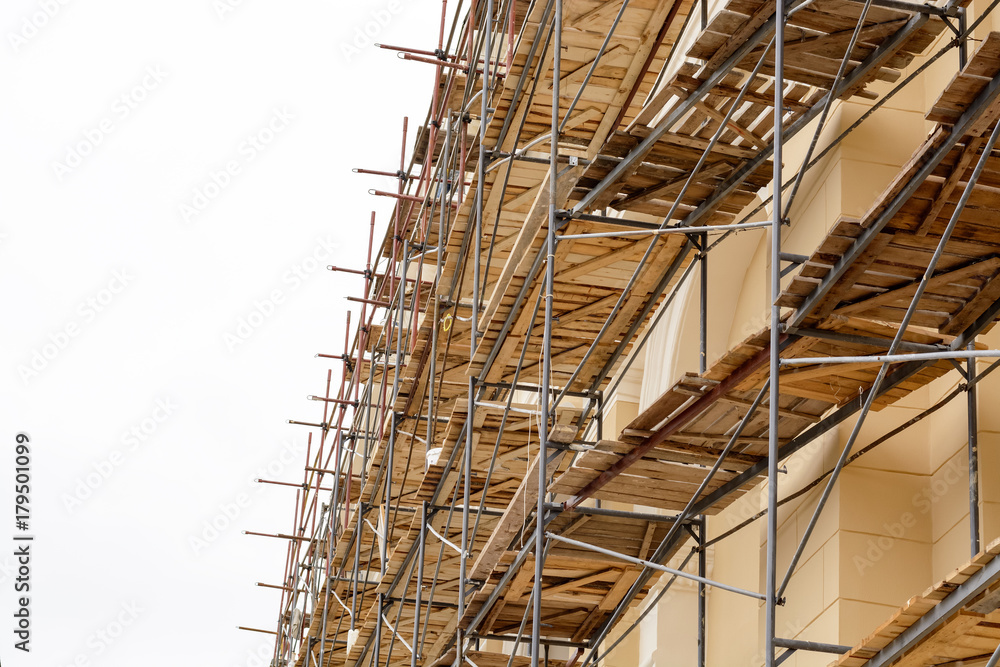 Metal scaffolding with wooden decking built around a historic building for restoration work and renovation of the facade. Construction works. Building construction. Metal scaffolding with wooden decking built around a historic building for restoration work and renovation of the facade. Construction works. Building construction.