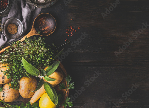 Food and cooking background with vegetables , flavor herbs and cooking spoon on dark rustic background, top view, place for text