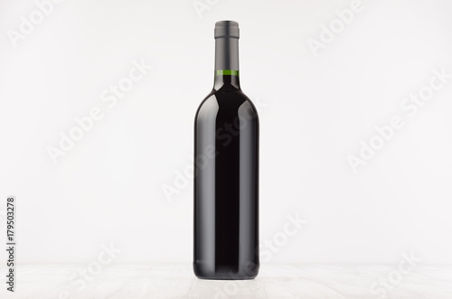 Black wine bottle with red wine on white wooden board, mock up. Template for advertising, design, branding identity.