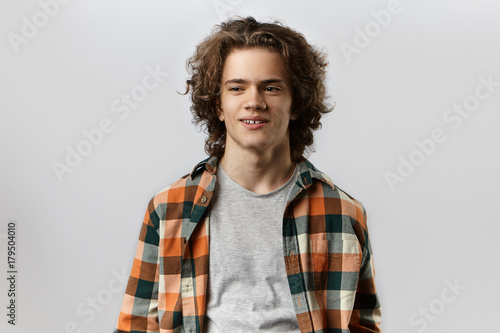 People, youth, happiness and modern lifestyle concept. Isolated portrait of handsome young male wearing stylish clothes, posing at blank studio wall, having happy joyful expression on his cute face