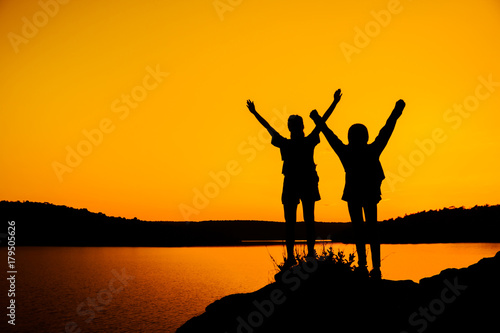 Silhouette two girls join hands to celebrate the success of the trip.