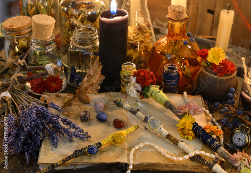 Magic wands, open diary book, lavender flowers and black candle on witch table