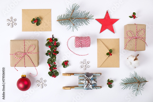 Christmas happy new year composition. Christmas gifts pine branch   red balls  envelope  white wood snowflakes  ribbon  red berries and present labels. Top view  flat lay  copy space.