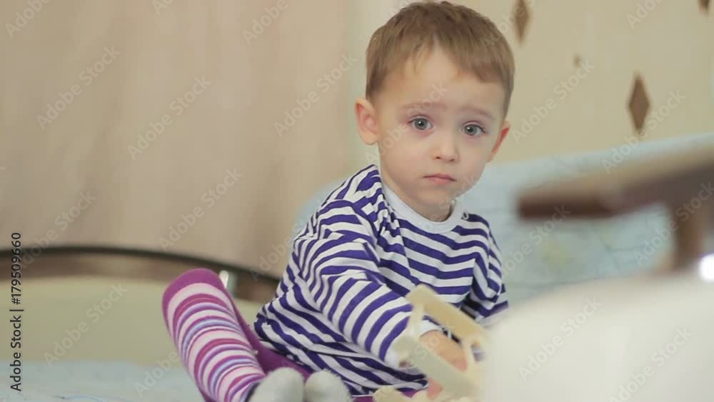 The child sits on the bed thoughtfully, looking at one point. The boy is thinking something The child sits on the bed thoughtfully, looking at one point. The boy is thinking something