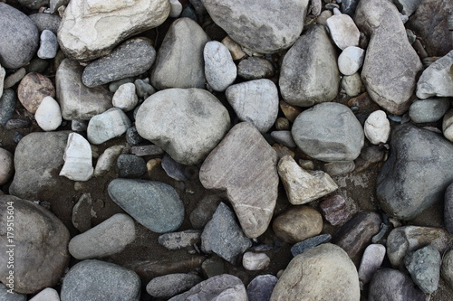 Grey and white stones on river beach as stone background texture.