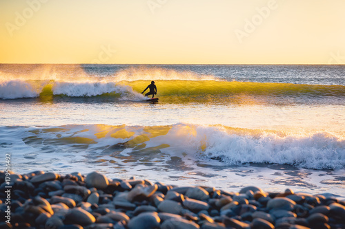 Canvas Print Surfer on the ocean wave at sunset or sunrise