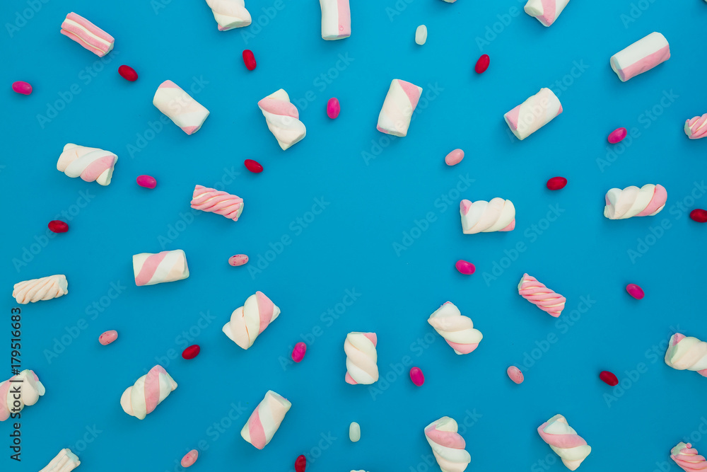 Colored candy and marshmallow on blue background. Flat lay, top view Colored candy and marshmallow on blue background. Flat lay, top view
