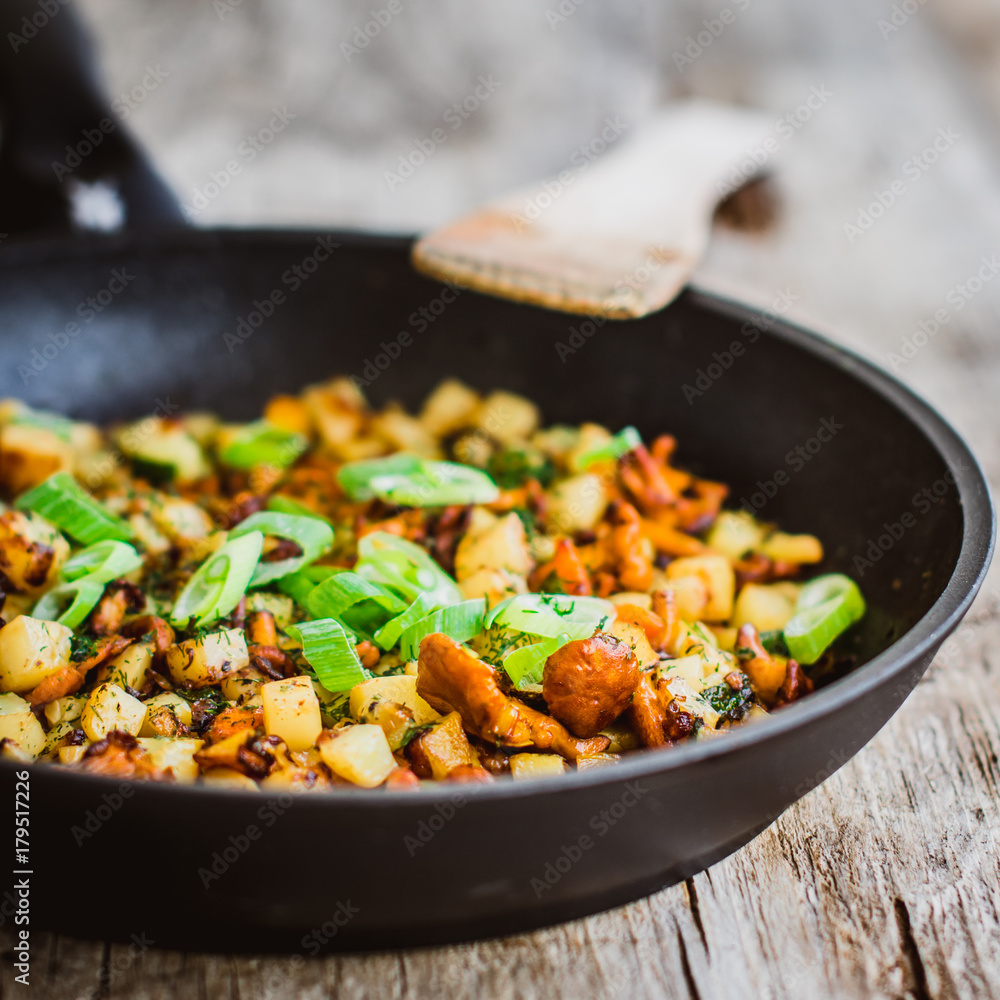 rosted chanterelles and potatoes with spring onions served in a black pan