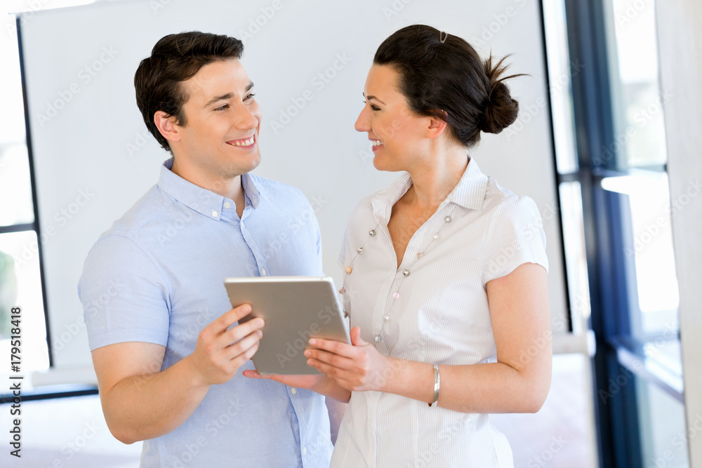 Young man and woman with touchpad standing in office Young man and woman with touchpad standing in office