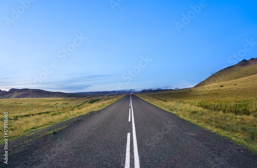 middle of th road with green field and blue sky in Iceland without car