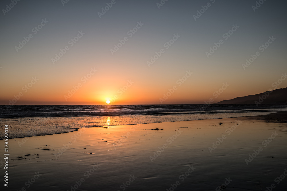 Red Yellow Orange Sunset Over Water With Waves On Shoreline Wet Sand On Beach Reflecting Sunset