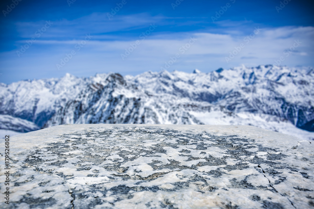 a stone tabletop with space for your product or advertising text. View of winter alpine mountains. Beautiful December sky in blue color. a stone tabletop with space for your product or advertising text. View of winter alpine mountains. Beautiful December sky in blue color.