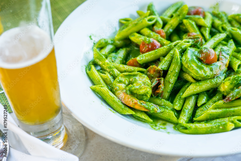 Vegetable penne pasta in basilica sauce with tomatoes decorated with parsley on a wooden table in restaurant Vegetable penne pasta in basilica sauce with tomatoes decorated with parsley on a wooden table in restaurant