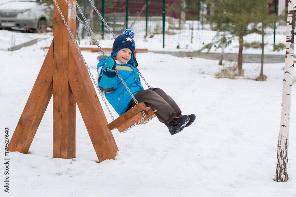 Happy child on swings at a winter park