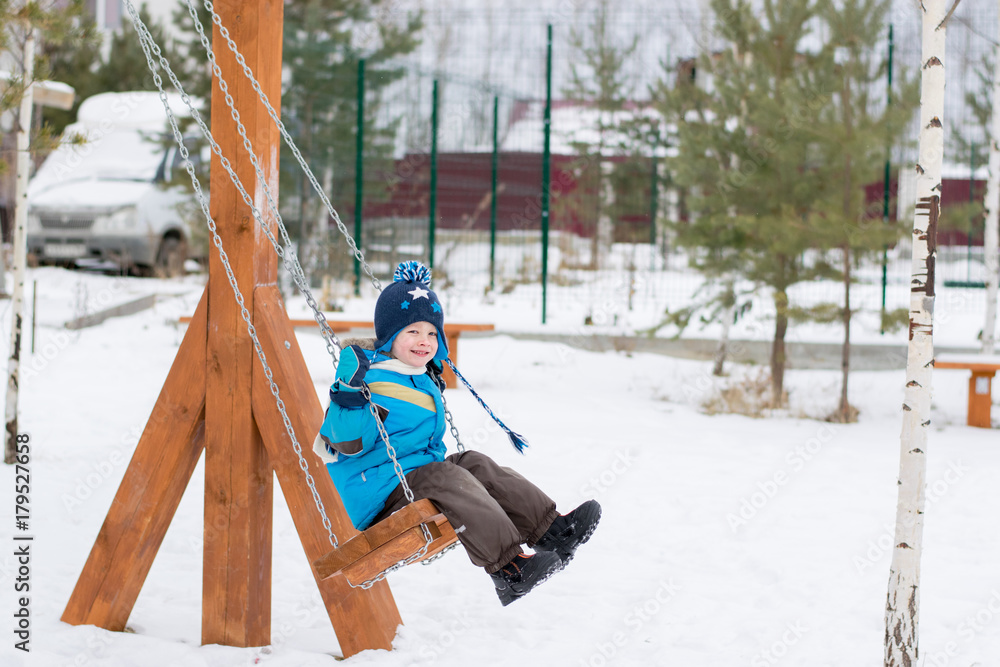 Happy child on swings at a winter park