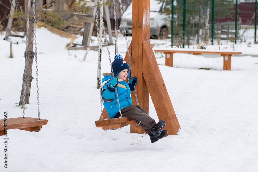 Happy child on swings at a winter park