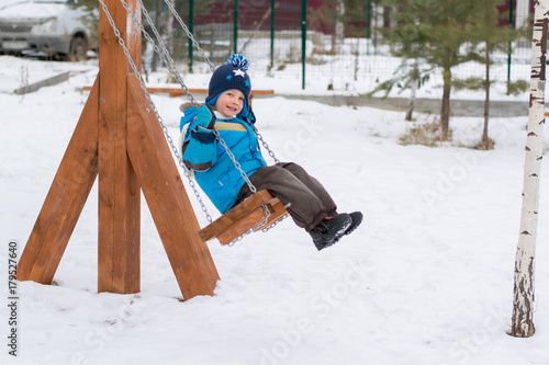 Happy child on swings at a winter park
