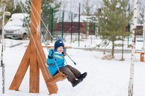 Obraz na płótnie Happy child on swings at a winter park w salonie