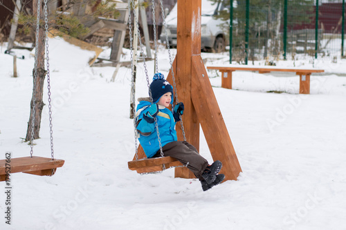 Happy child on swings at a winter park