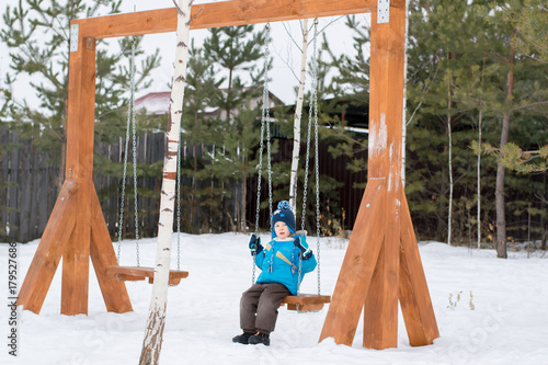 Happy child on swings at a winter park