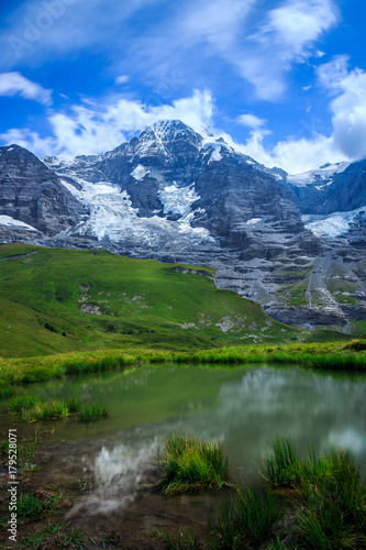 Mountain Monch (4.107m - 13.474ft) and Jungfraujoch + reflection in water in the Bernese Alps in Summer. Kleine Scheidegg, Bernese Oberland, Switzerland. © Steven