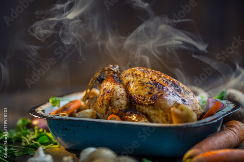 Roast whole turkey or  chicken in old pan with vegetables photo