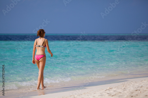 Young woman walking on the beach © 25ehaag6