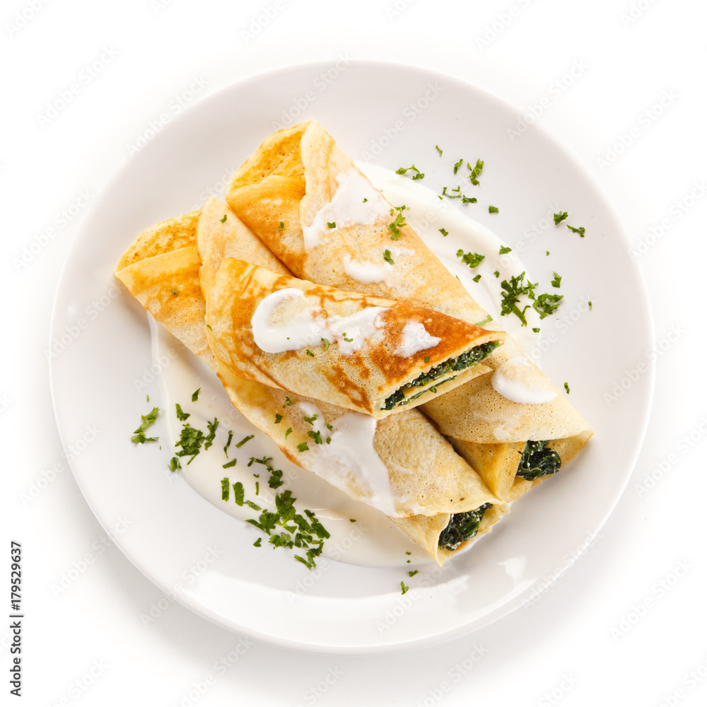 Crepes with spinach and feta cheese on white background