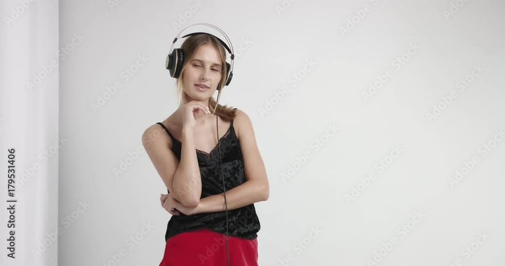 Attractive girl in red silky boxer shorts and black sexy cami dancing to music in headphones isolated on white Attractive girl in red silky boxer shorts and black sexy cami dancing to music in headphones isolated on white
