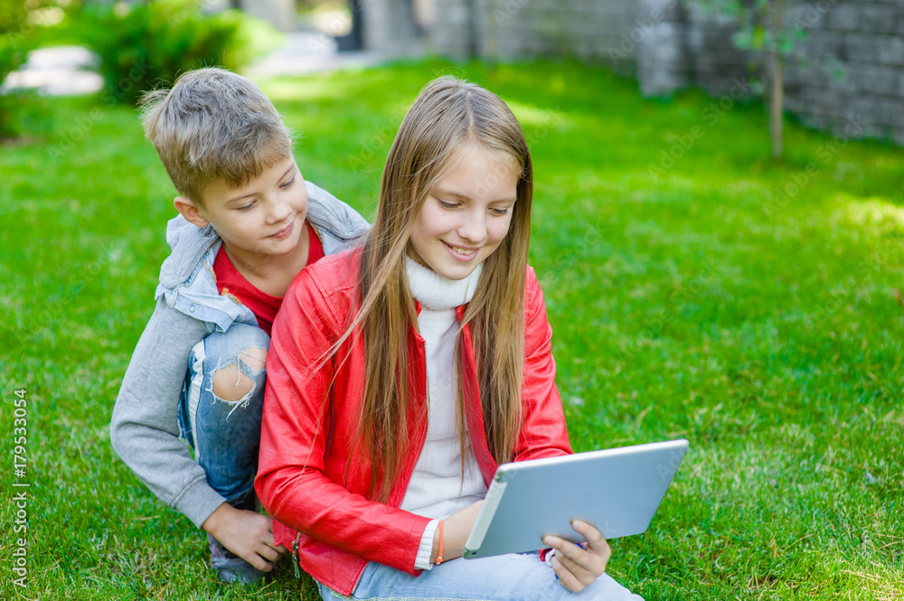 children communicate using a tablet computer on green grass children communicate using a tablet computer on green grass