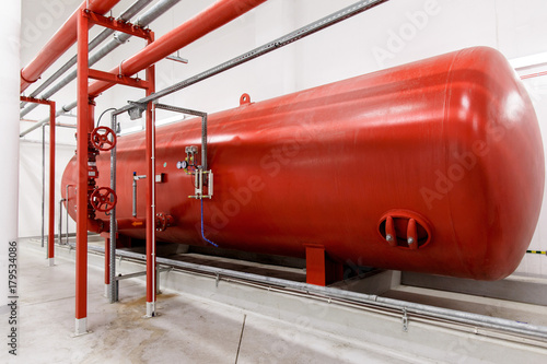 Industrial big red tank inside factory. Tank for water under high pressure. Fire systems.