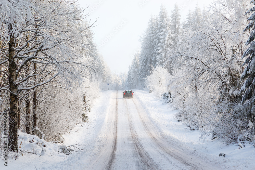 Obraz premium Car driving on a winter road in the woods