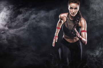 A strong athletic, woman sprinter, running on black background wearing in the sportswear, fitness and sport motivation. Runner concept with copy space.