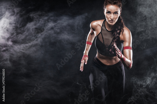 A strong athletic, woman sprinter, running on black background wearing in the sportswear, fitness and sport motivation. Runner concept with copy space.