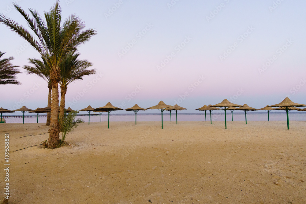 sunset glow, parasols on beautiful sandy beach