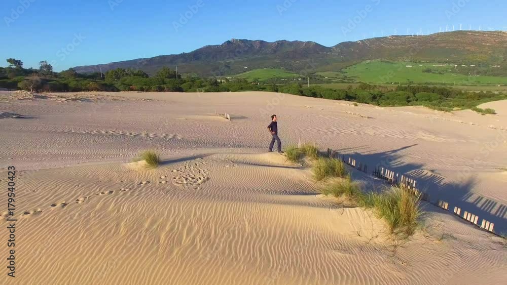 Aerial view of young man in the top of a dune sand with opened arms. Concept freedom Aerial view of young man in the top of a dune sand with opened arms. Concept freedom