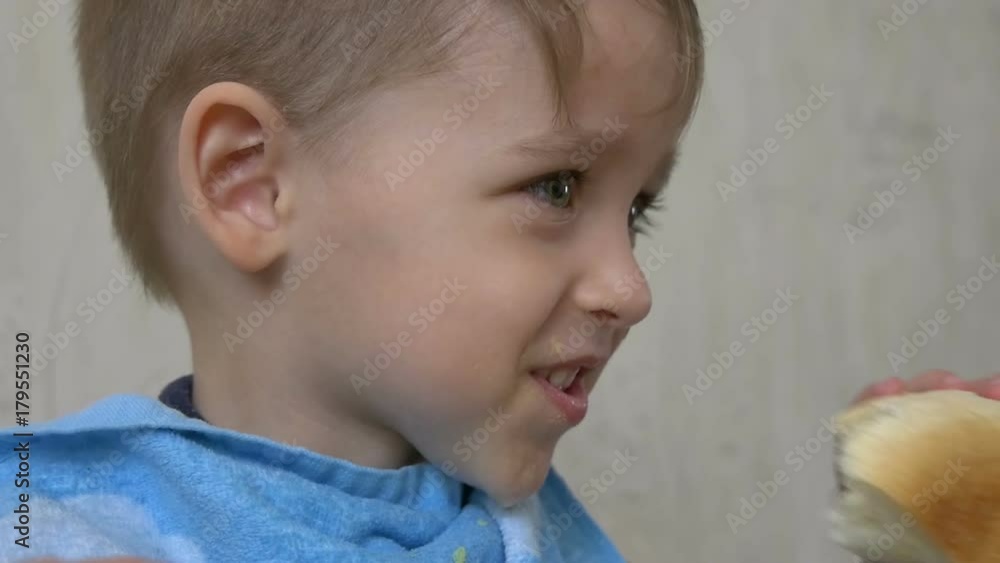 Child boy eats bread or rolls close-up Child boy eats bread or rolls close-up
