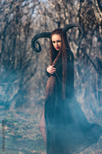 beautiful woman dressed as a fairy witch in raincoat and with horns for Halloween photo